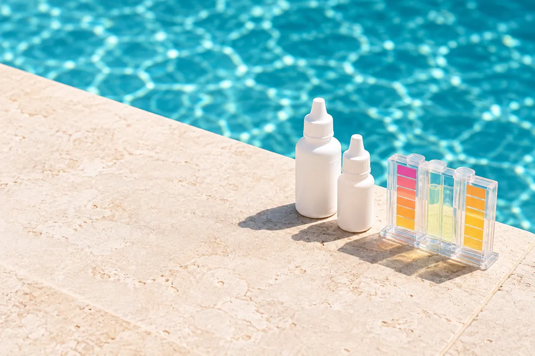 Water testing kit on limestone beside a swimming pool