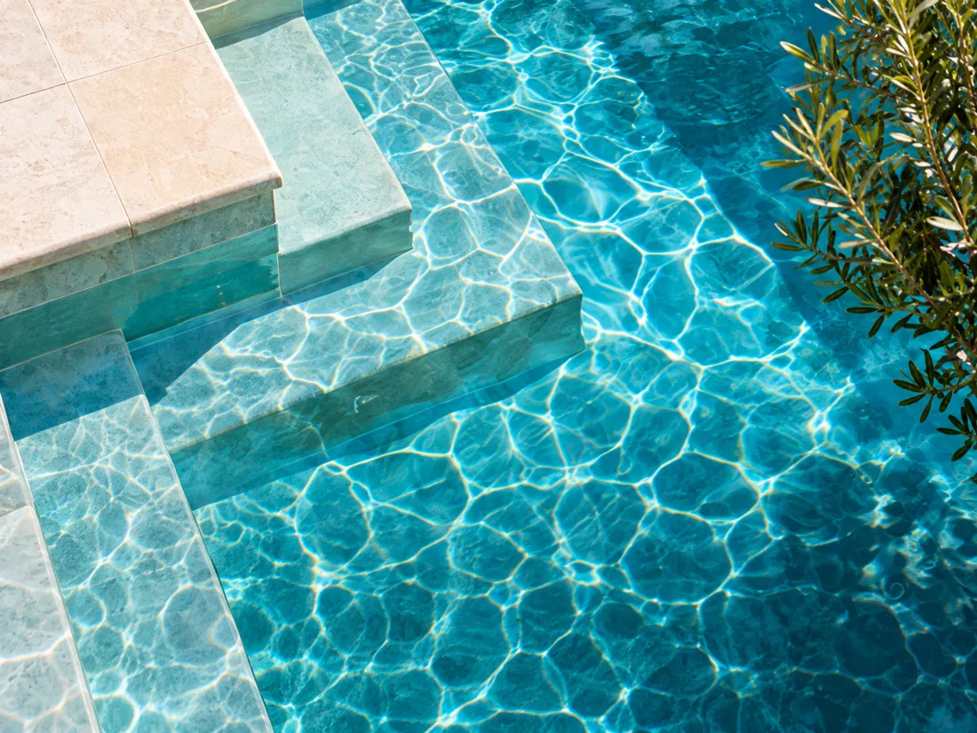 Sunlit limestone steps descending into clear turquoise pool water